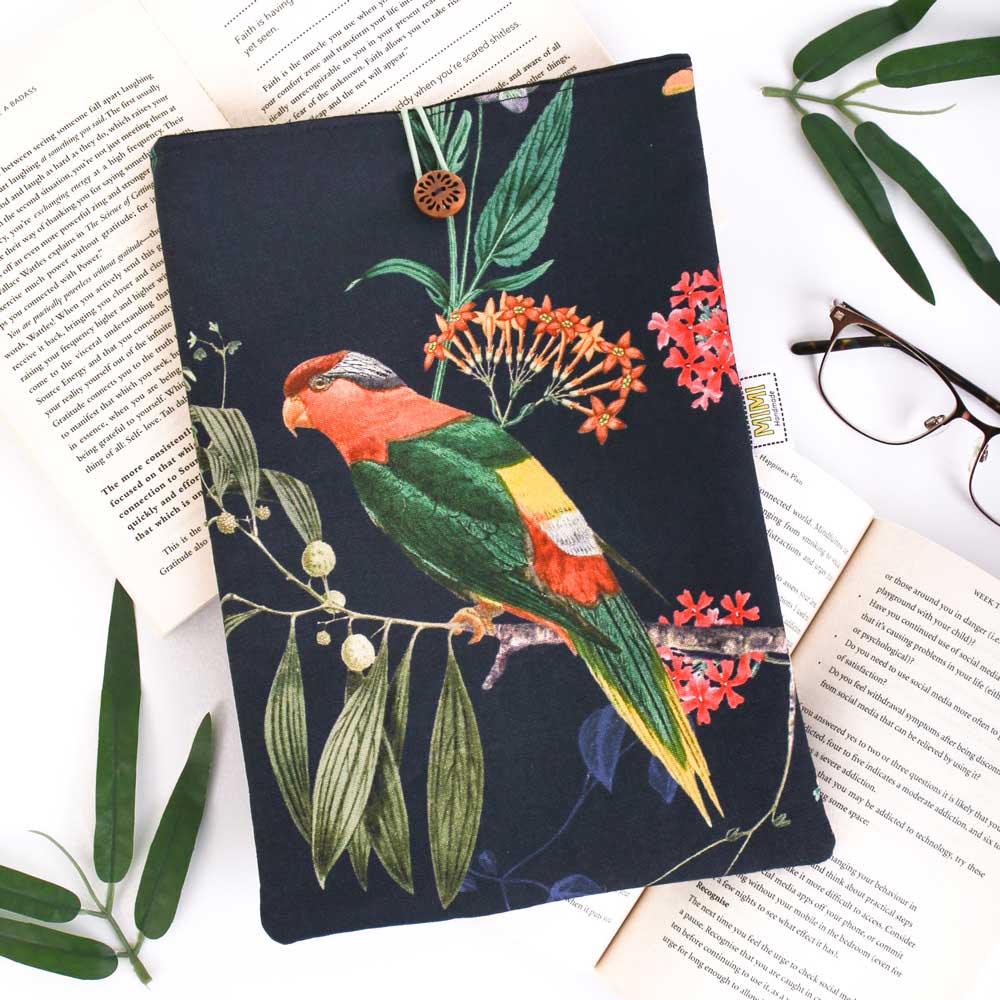 Book sleeve with a colourful parrot illustration on a floral background, placed on open books.