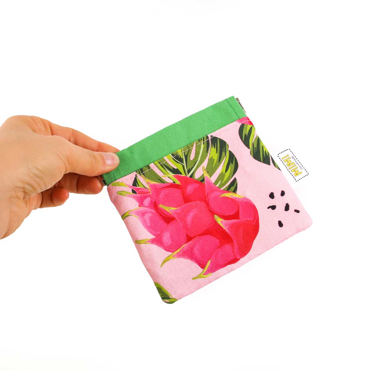 Hand holding a small pouch with pink dragon fruit design on a white background