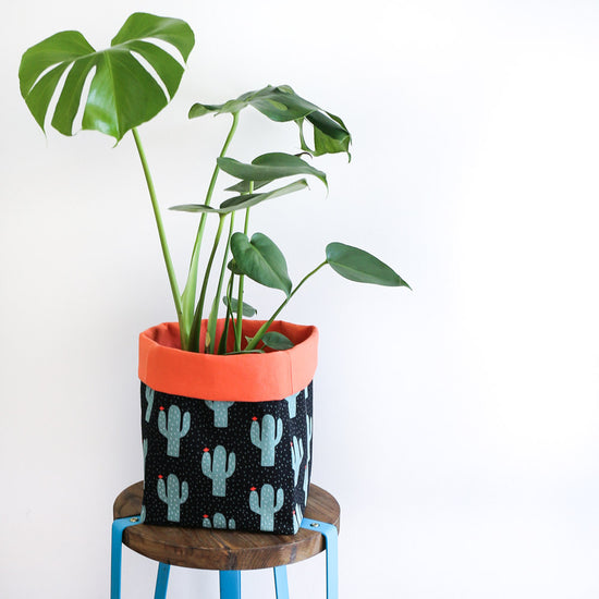 monstera plant in a black and orange cactus fabric plant pot cover
