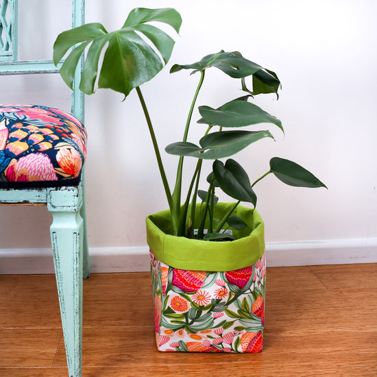 monstera plant in bright green multi-coloured square fabric pot plant cover next to a mint chair-australiana homewares