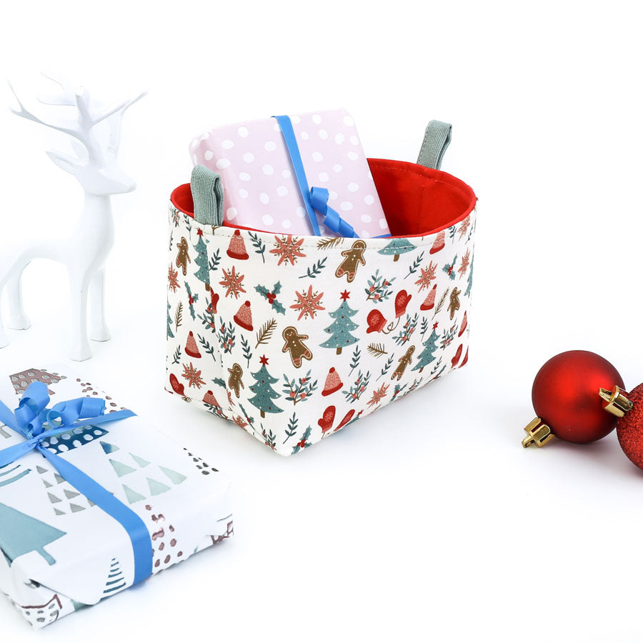 small-decorative-Christmas-basket-by-MIMI-Handmade-featuring-gingerbread-men-and-Xmas-trees-fabric-pattern-with-gifts-inside-the-basket-and-on-table