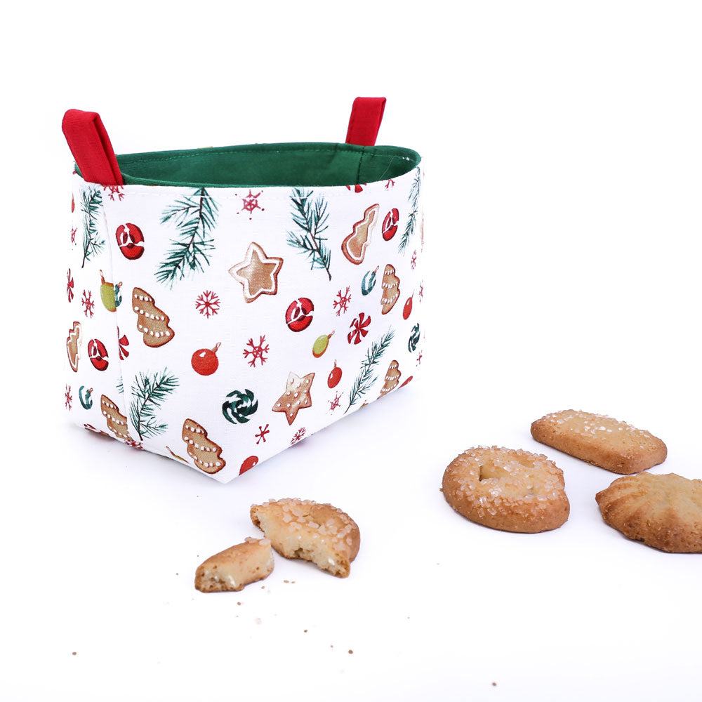 small-white-green-and-red-Christmas-basket-featuring-Xmas-cookies-fabric-pattern-with-half-eaten-biscuits-on-white-table