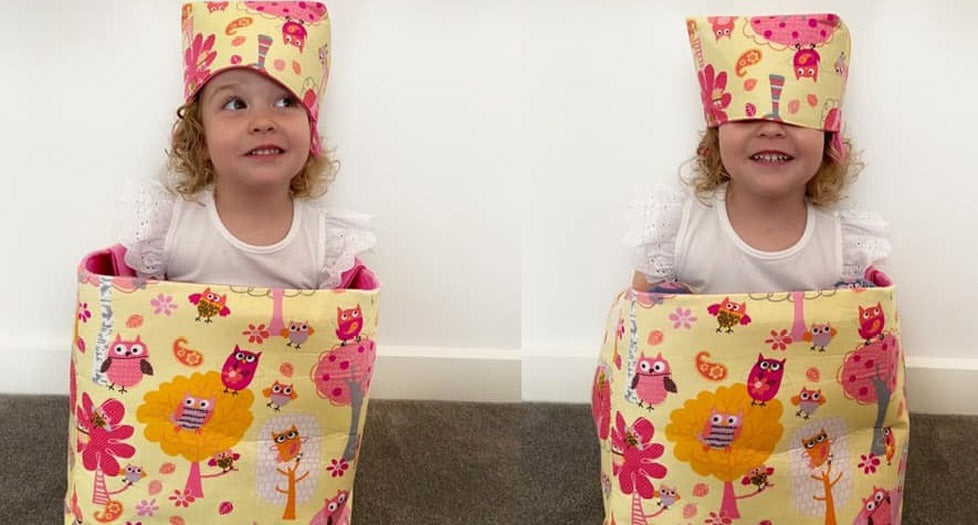 little girl inside a large toy storage basket with a smaller basket on her head MIMI Handmade Baskets