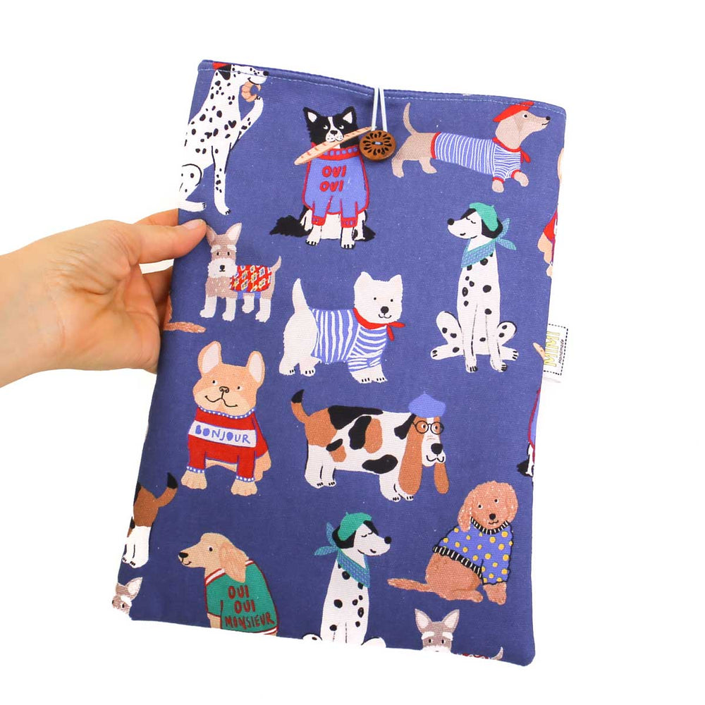 
                  
                    Hand holding a blue book sleeve with dog illustrations on a white background
                  
                