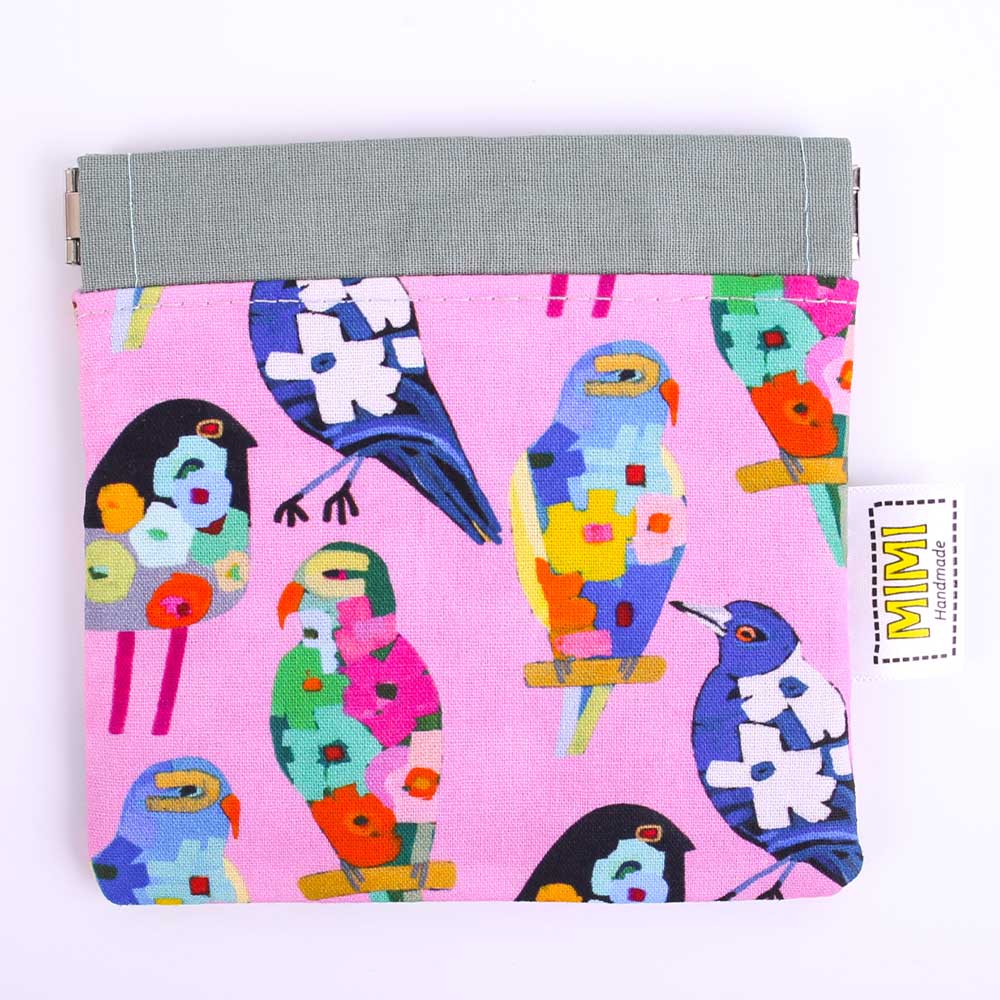 Colourful bird-patterned pouch on a pink background