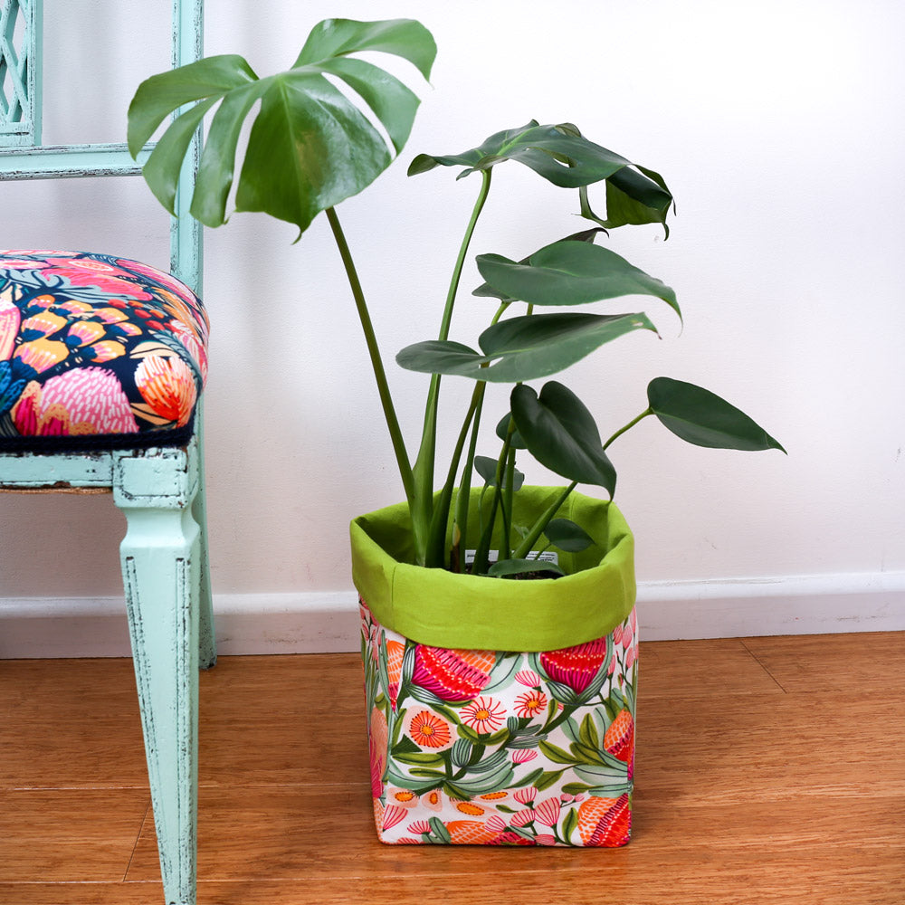 monstera plant in bright green multi-coloured square fabric pot plant cover next to a mint chair-australiana homewares